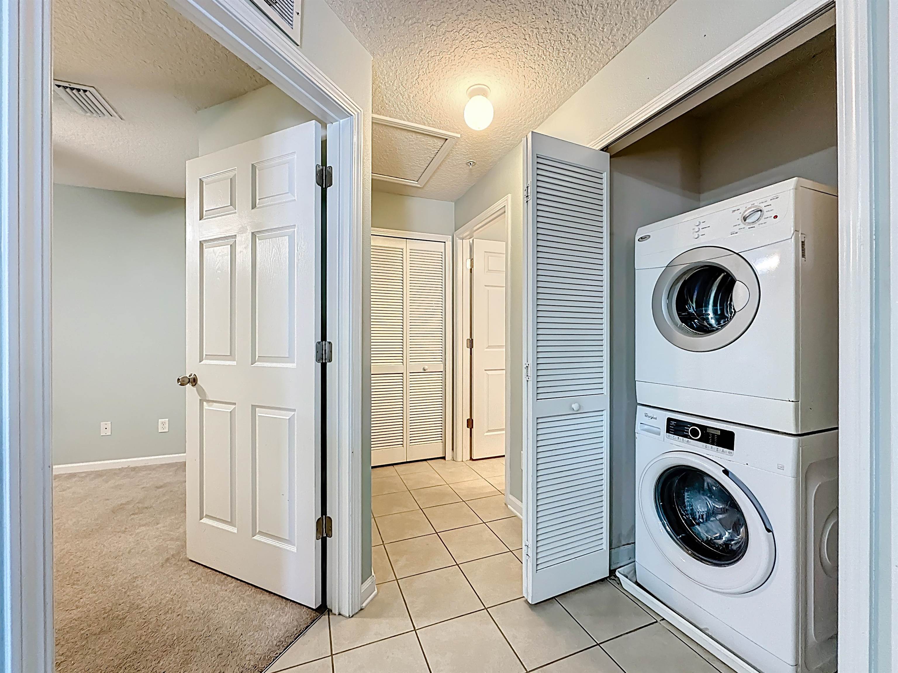 240 Golden Lake Loop St. Augustine, FL 32084 - Photo 25 of 31 Laundry area featuring stacked washer and clothes dryer, a textured ceiling, light colored carpet, and light tile patterned floors
