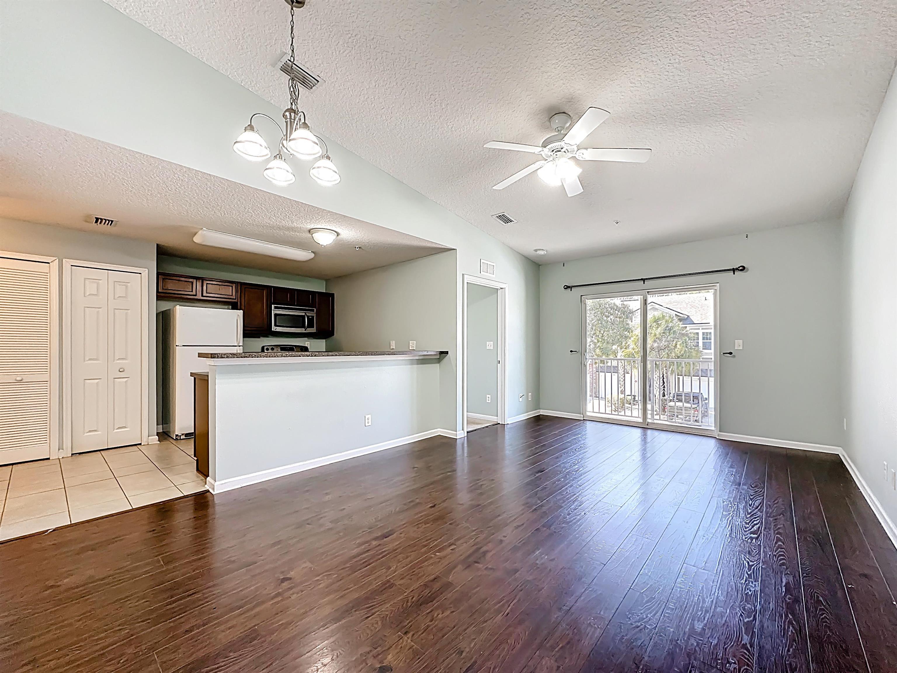 240 Golden Lake Loop St. Augustine, FL 32084 - Photo 5 of 31 Unfurnished living room featuring ceiling fan, dark wood-style flooring, and hanging lights