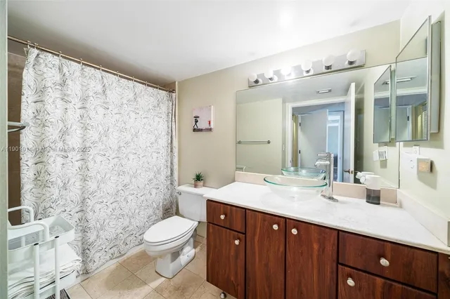 a spacious bathroom with a granite countertop sink toilet a large mirror and shower