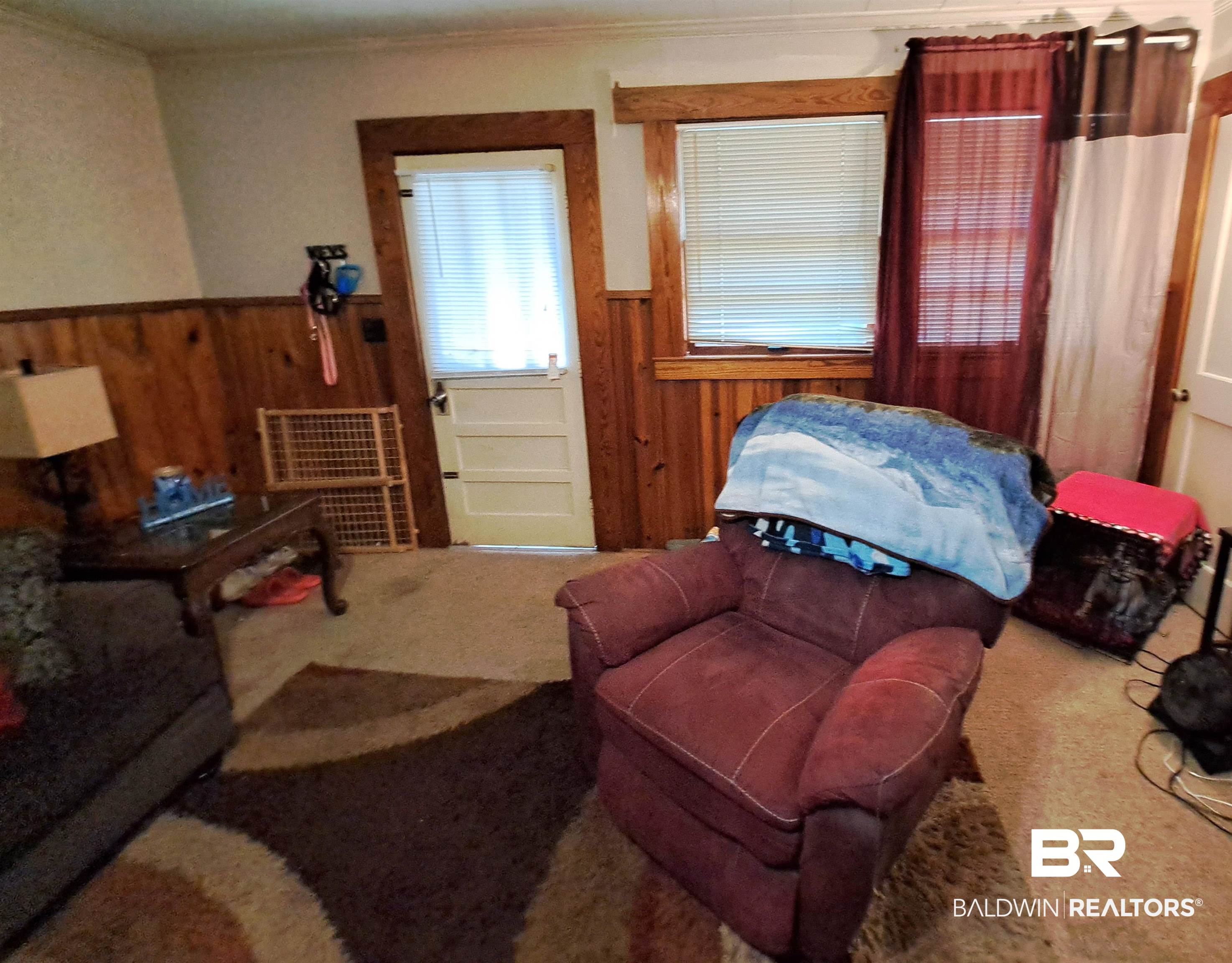 309 Bellview Avenue Evergreen, AL 36401 - Photo 5 of 27 Living room featuring wooden walls, a wainscoted wall, carpet flooring, and crown molding
