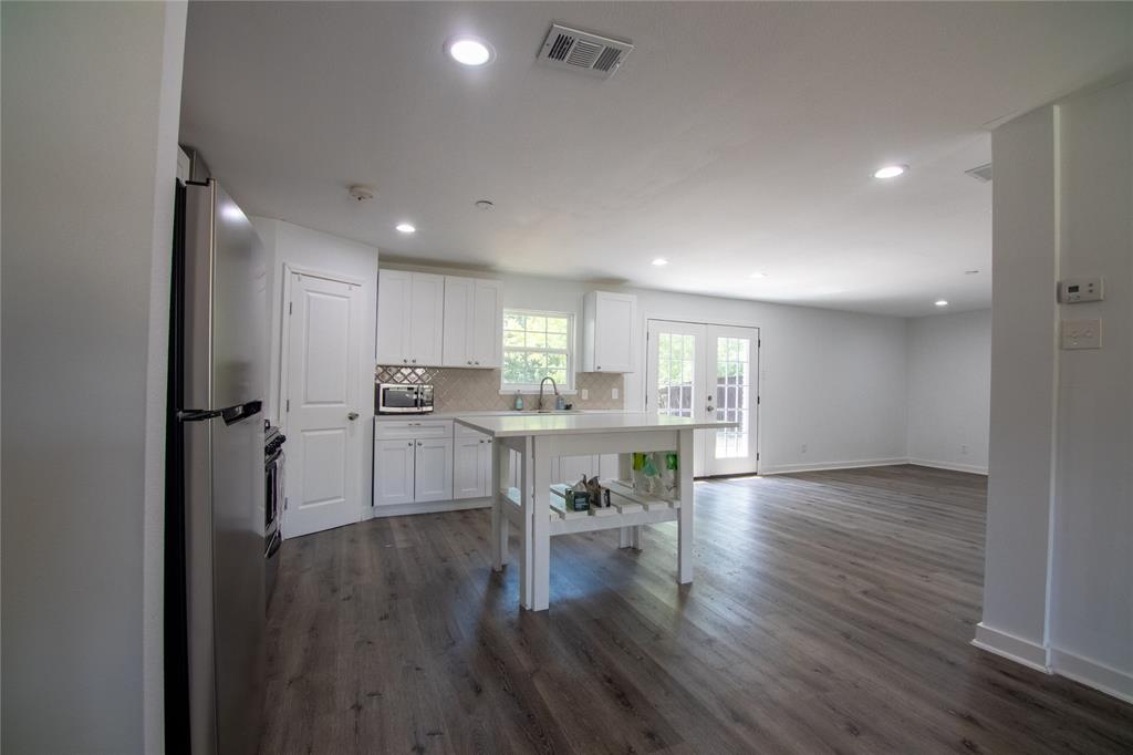 a kitchen with a refrigerator and white cabinets with wooden floor