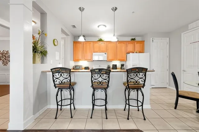 a dining room filled a chandelier and kitchen view