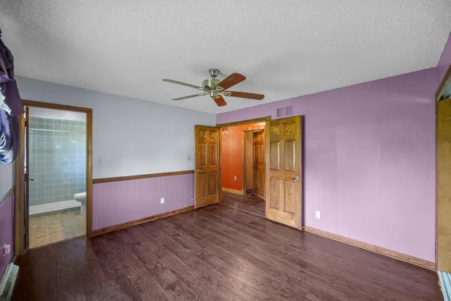 an empty room with wooden floor and a ceiling fan