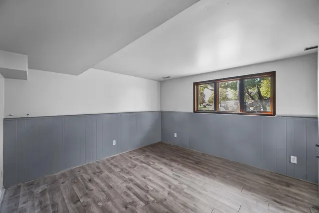 a view of empty room with wooden floor and fan
