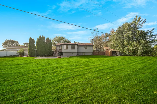 a view of a green field with house in the background