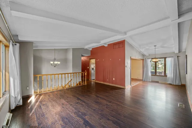 a view of an empty room with wooden floor and windows