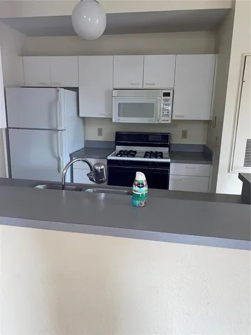 a kitchen with a sink a stove and white cabinets