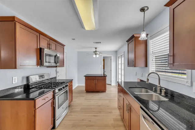 a kitchen with stainless steel appliances granite countertop a stove a microwave and a sink