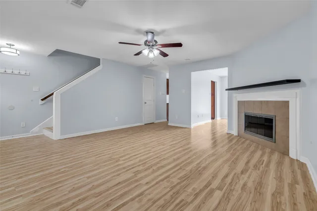 an empty room with wooden floor fan and windows