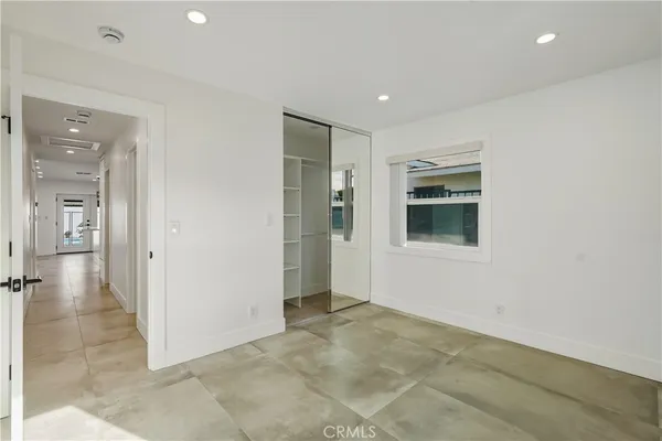 a view of an empty room with kitchen view and a window
