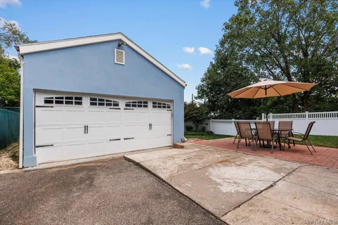 a backyard of a house with table and chairs under an umbrella