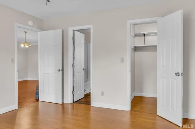 a view of an empty room with wooden floor and a bathroom
