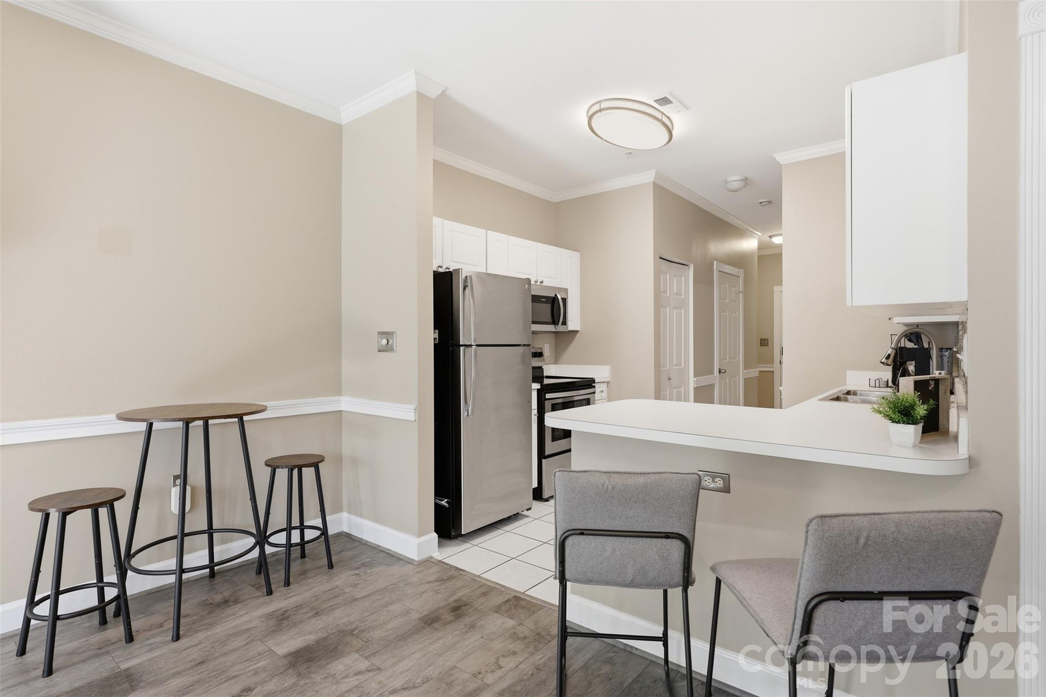 9054 Meadow Vista Road Charlotte, NC 28213 - Photo 15 of 30 a white kitchen with a dining table wooden floor and stainless steel appliances