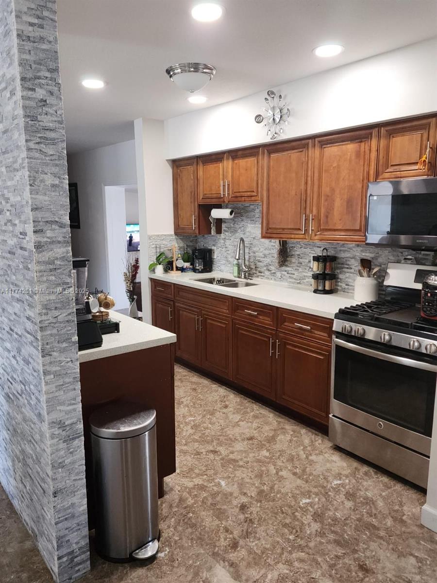 341 West 59th Street Hialeah, FL 33012 - Photo 5 of 44 a kitchen with stainless steel appliances a stove sink microwave and cabinets