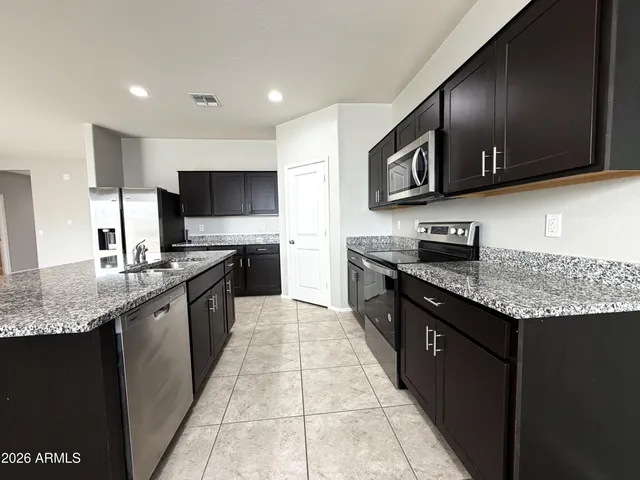 a large kitchen with stainless steel appliances granite countertop a stove a sink dishwasher a microwave oven and a refrigerator