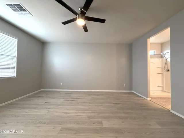 an empty room with wooden floor fan and windows