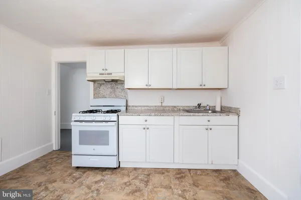 a kitchen with granite countertop white cabinets and white appliances