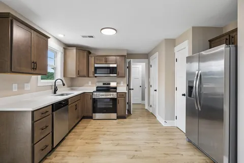 a kitchen with stainless steel appliances granite countertop a refrigerator stove top oven and sink