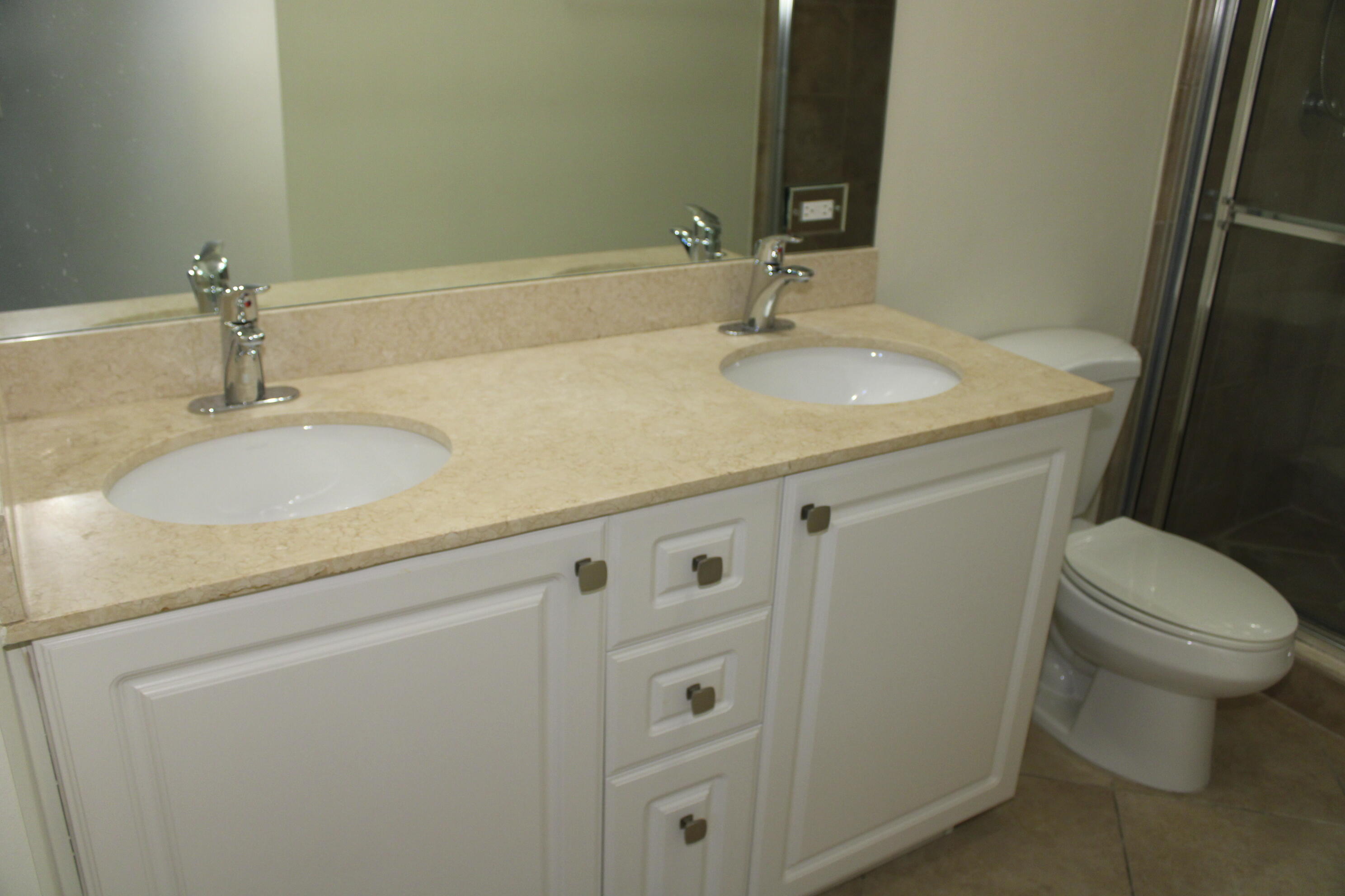 1690 Renaissance Commons Boulevard, Unit 1429 Boynton Beach, FL 33426 - Photo 20 of 23 a bathroom with a granite countertop toilet sink and mirror