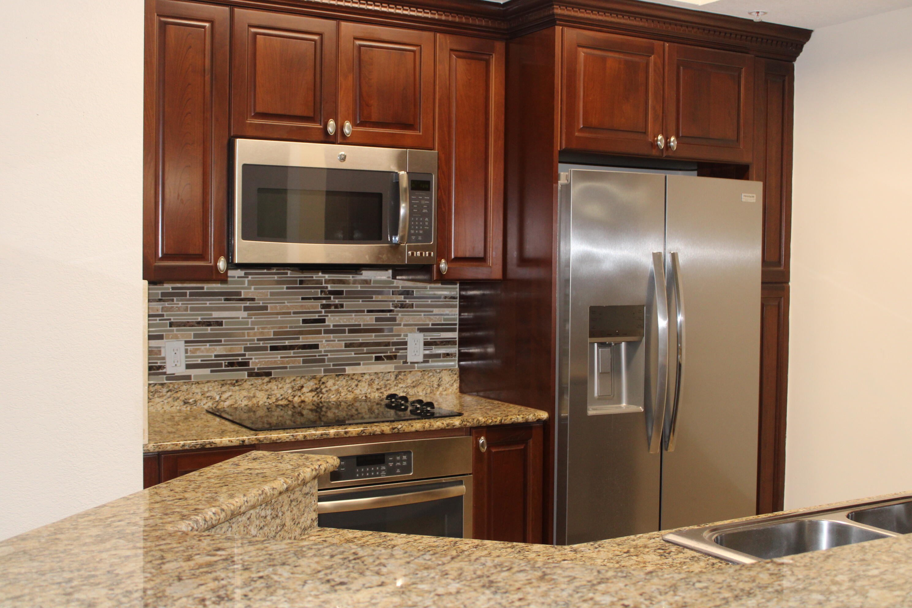 1690 Renaissance Commons Boulevard, Unit 1429 Boynton Beach, FL 33426 - Photo 2 of 23 a kitchen with granite countertop a stove and a microwave