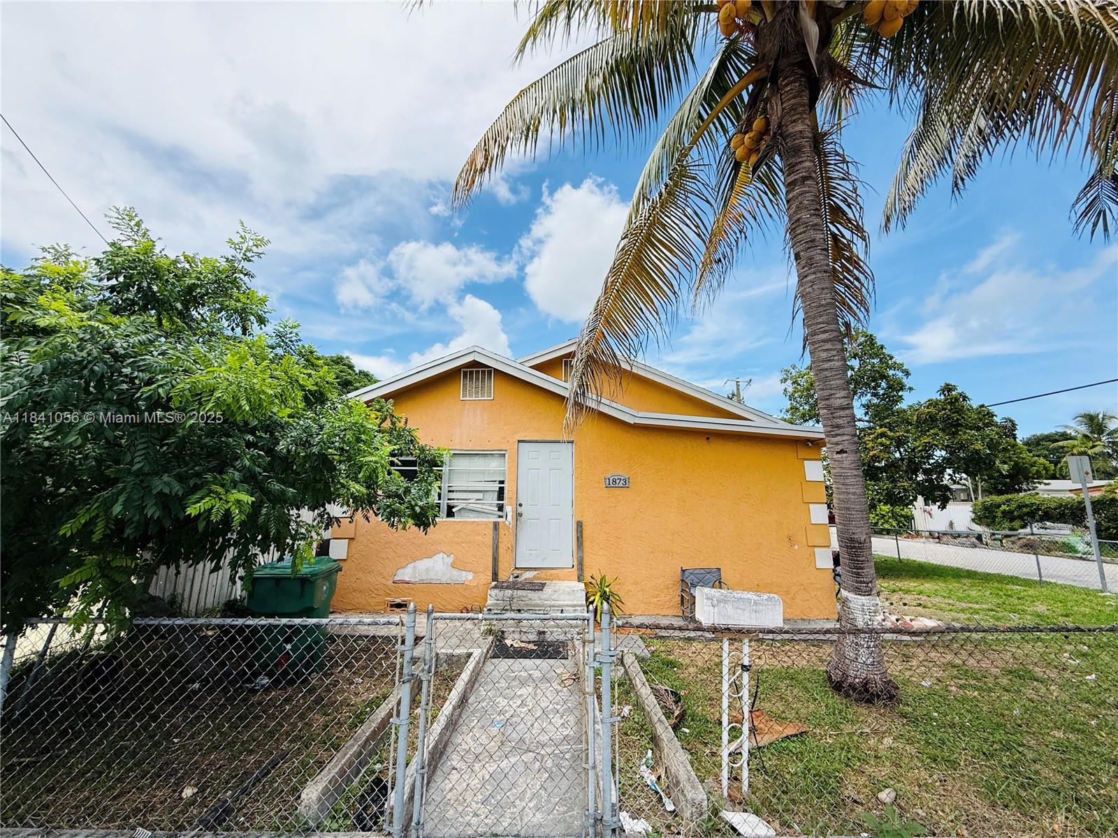 a view of a house with a yard and palm trees
