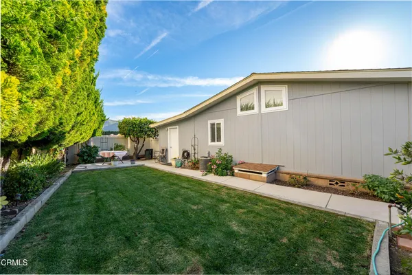 a backyard of a house with table and chairs plants and large tree