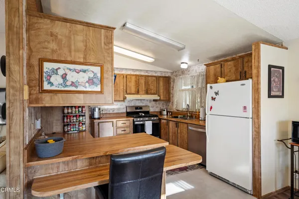 a kitchen with stainless steel appliances granite countertop a refrigerator a stove a sink a microwave and with wooden cabinets