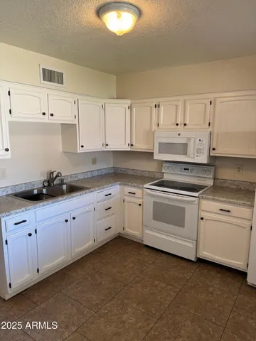 a kitchen with granite countertop white cabinets and white appliances
