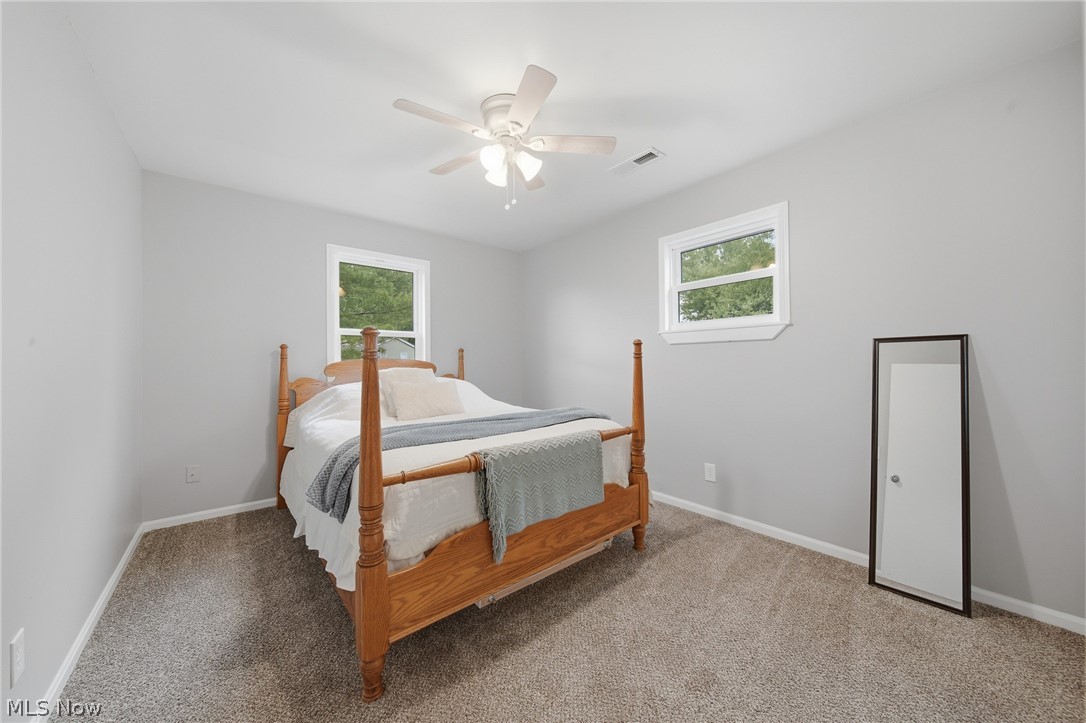 3471 State Rte 5 Newton Falls, OH 44444 - Photo 13 of 31 Bedroom featuring two windows, neutral gray walls, light brown carpet, and a ceiling fan with integrated lighting