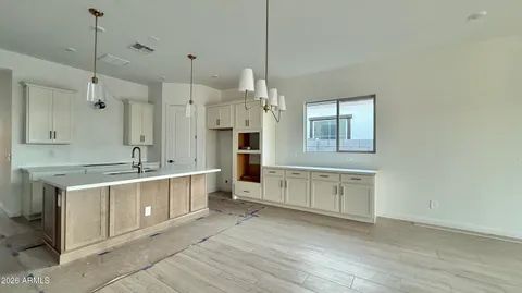 a large kitchen with a stove a sink dishwasher a refrigerator and white cabinets with wooden floor