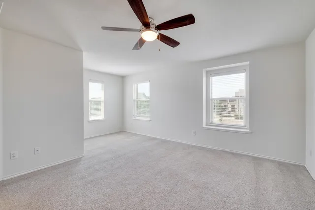 an empty room with a window and a fan