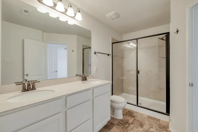 a bathroom with a double vanity sink mirror and toilet