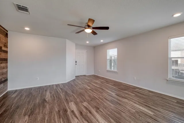 a view of empty room with wooden floor and fan