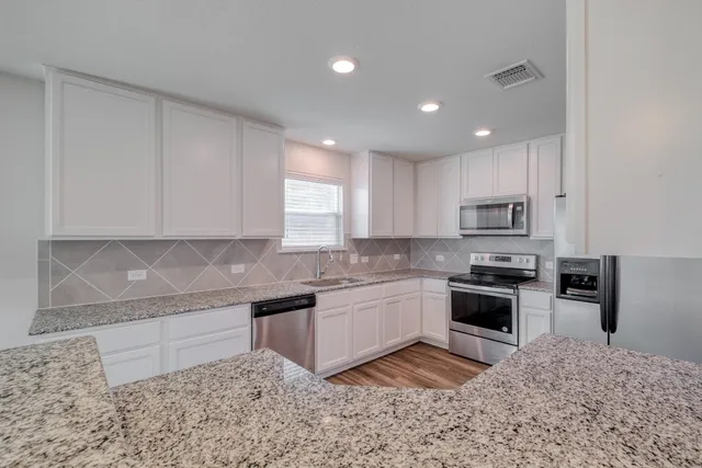 a large kitchen with granite countertop a stove sink and cabinets