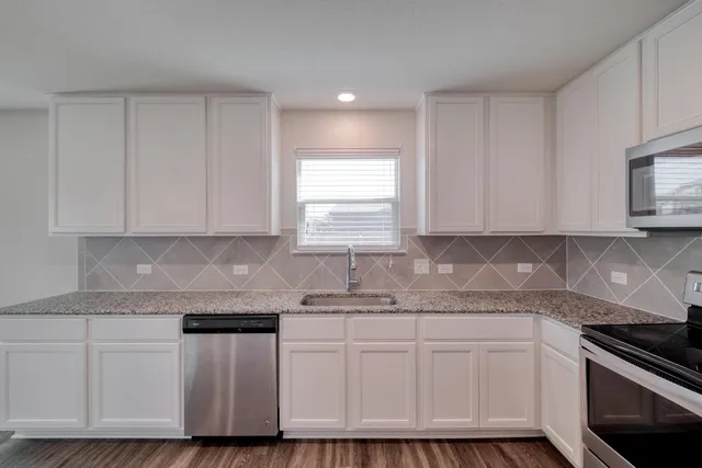 a kitchen with granite countertop white cabinets and white stainless steel appliances