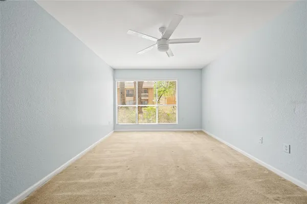 an empty room with a window and a ceiling fan