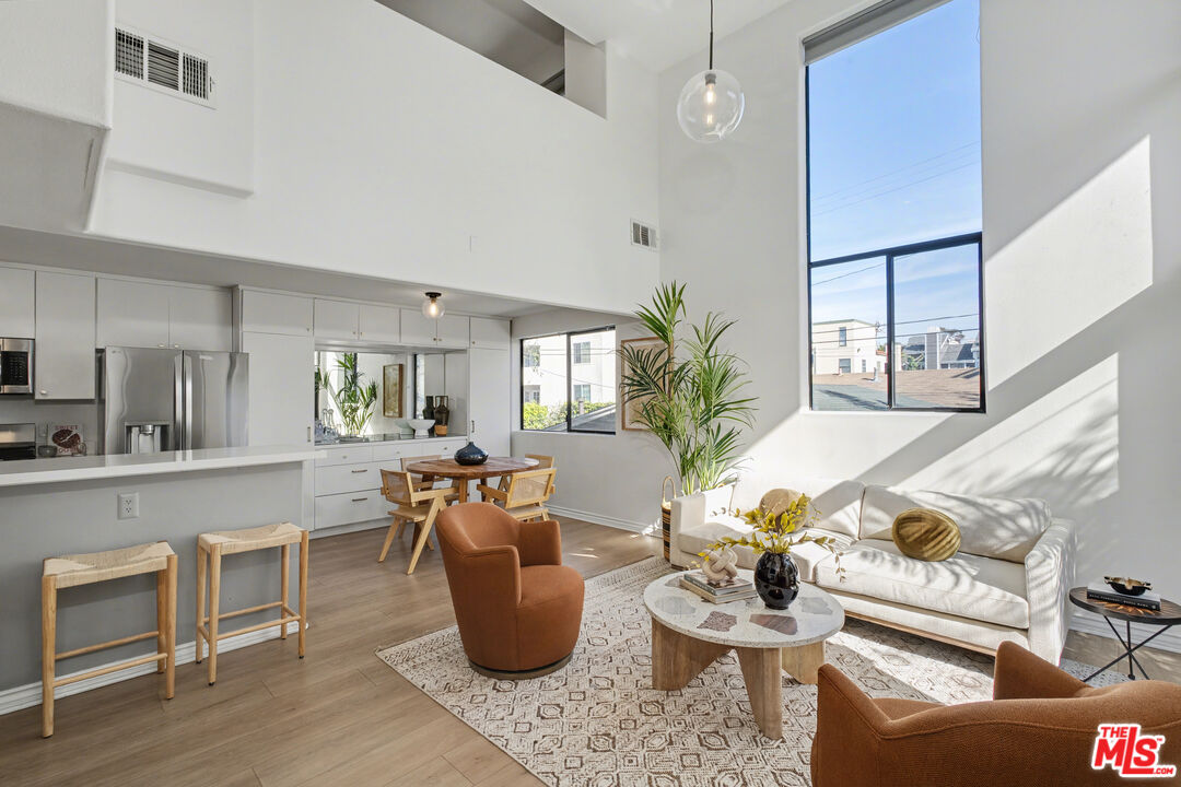 a living room with furniture a potted plant and kitchen view