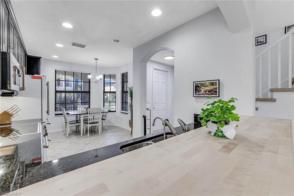 1307 Kendari Terrace Naples, FL 34113 - Photo 18 of 45 Kitchen with arched walkways, light tile patterned flooring, stainless steel appliances, and dark stone countertops