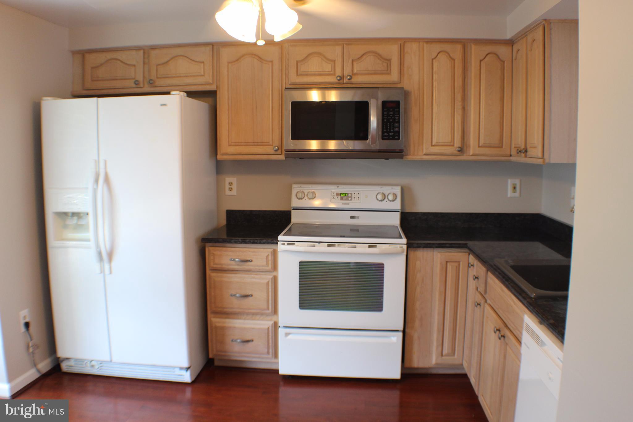 6308 Greenfield Road Elkridge, MD 21075 - Photo 2 of 14 a kitchen with stainless steel appliances white cabinets and a stove a refrigerator with wooden floors