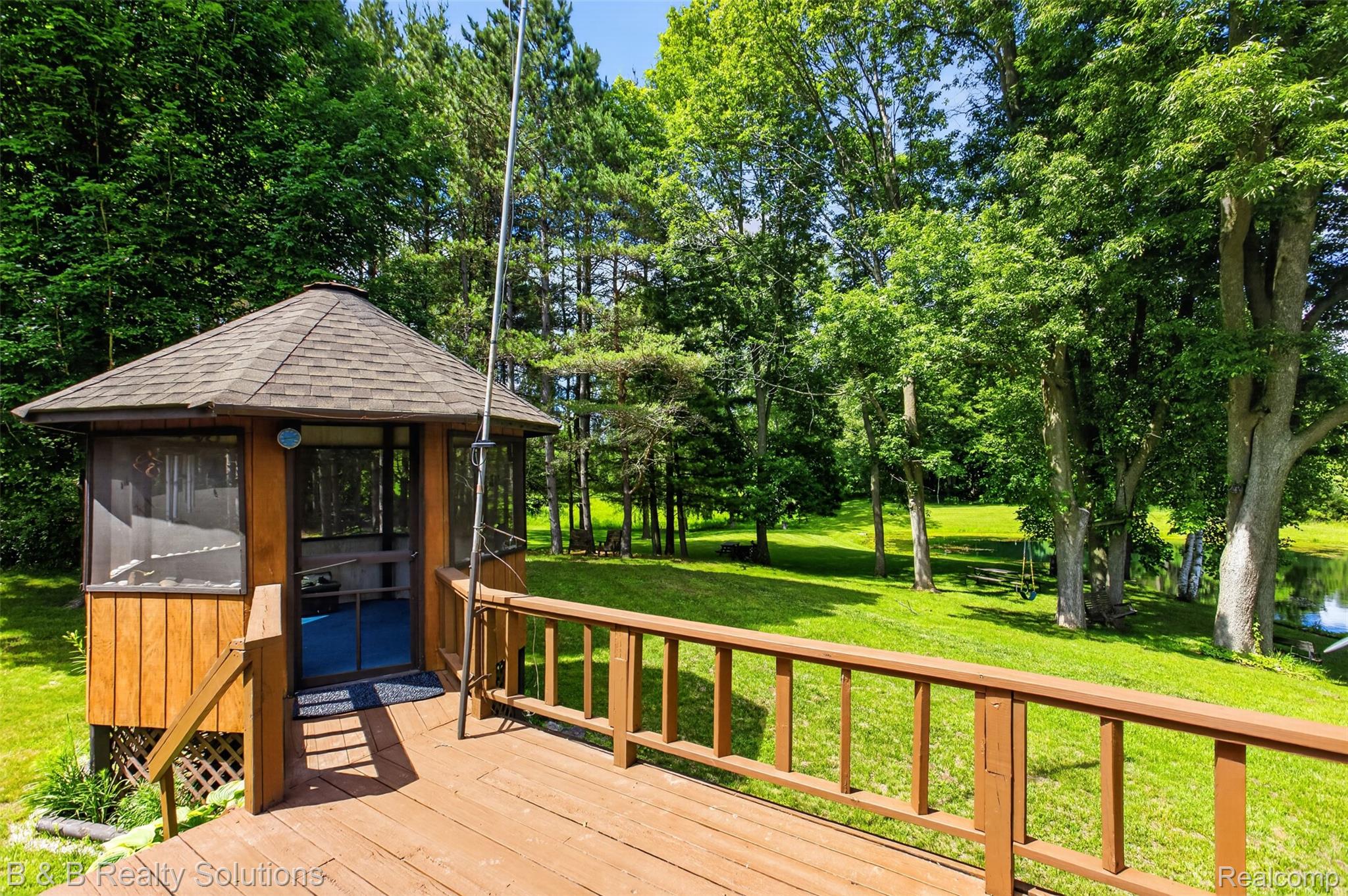 5544 Piersonville Road Columbiaville, MI 48421 - Photo 7 of 49 Wood deck with railing leading to a screened gazebo featuring a shingle roof