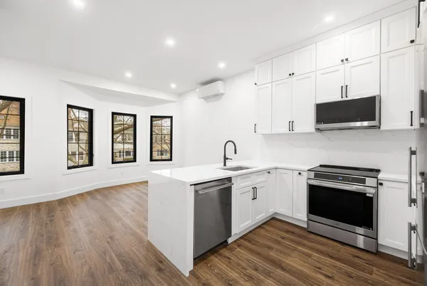 a kitchen with stainless steel appliances granite countertop a stove top oven a sink dishwasher and a microwave oven with wooden floor