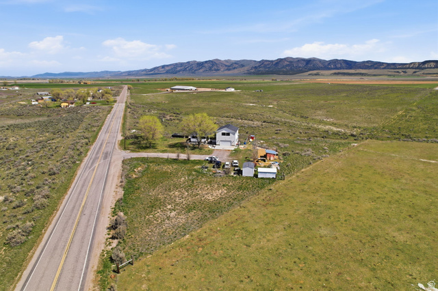 830 North Stone Road Snowville, UT 84336 - Photo 60 of 69 Aerial view of property and surrounding area featuring rural landscape and a mountainous background