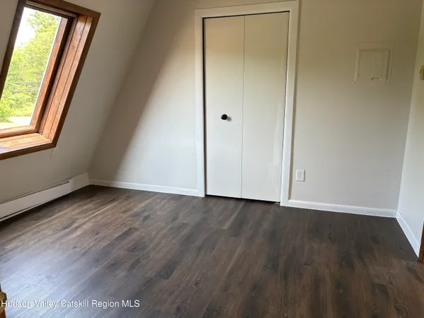 an empty room with wooden floor and window