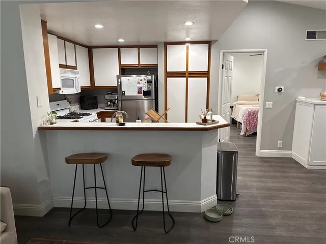 a kitchen with stainless steel appliances granite countertop a sink a stove a refrigerator and island with wooden floor