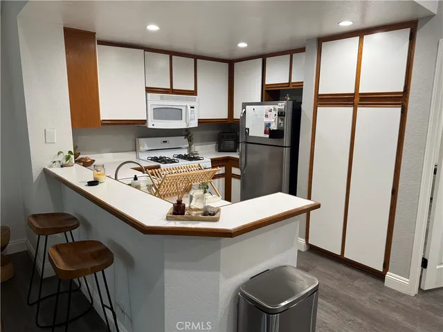 a kitchen with stainless steel appliances granite countertop a refrigerator a stove a sink dishwasher and a microwave with wooden floor