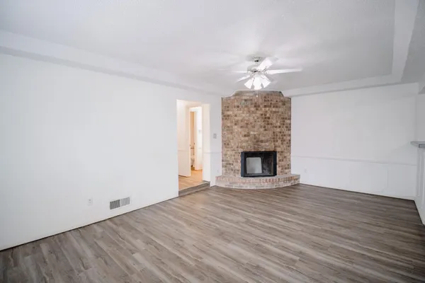 a view of an empty room with window and wooden floor