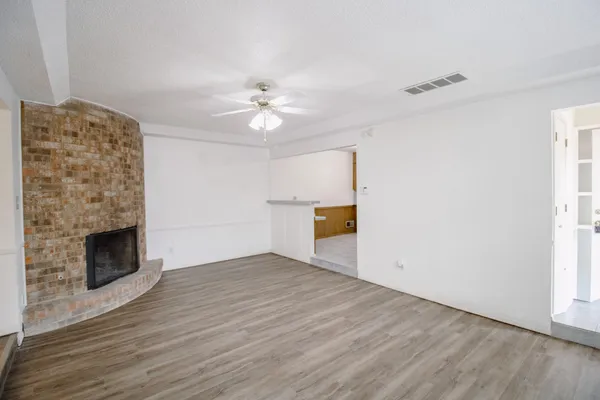 a view of empty room with wooden floor and fireplace