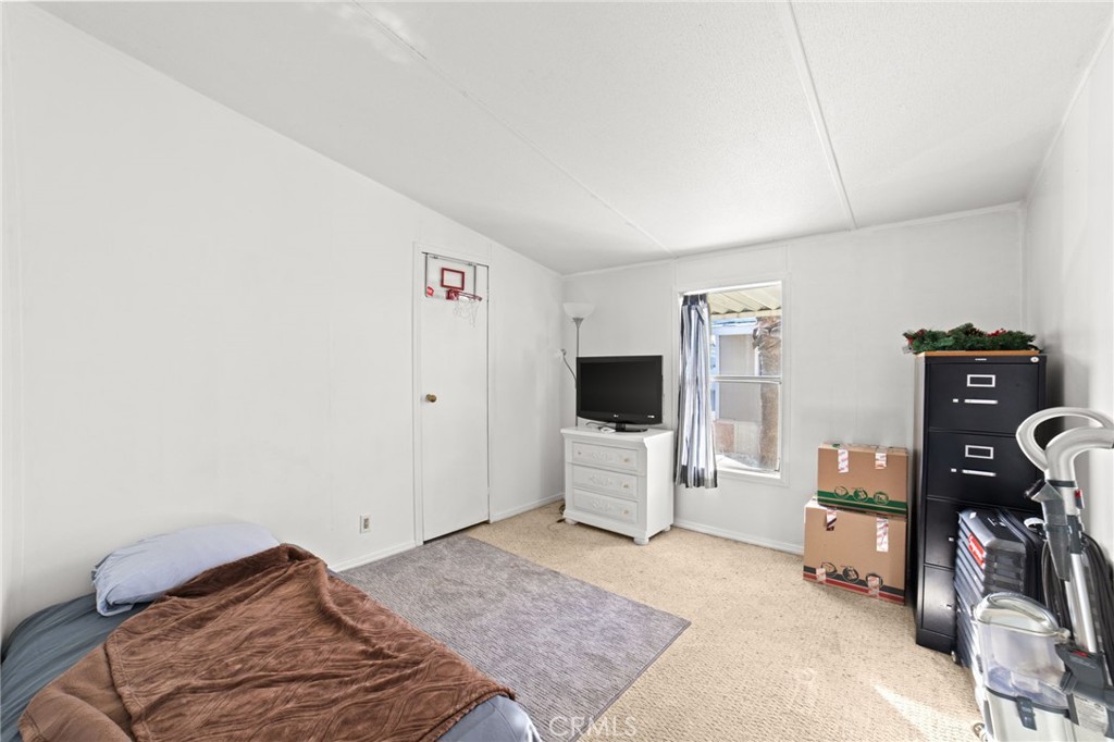 1155 South Riverside Avenue, Unit 22 Rialto, CA 92376 - Photo 23 of 34 a bedroom with a bed and a flat tv screen on the dresser