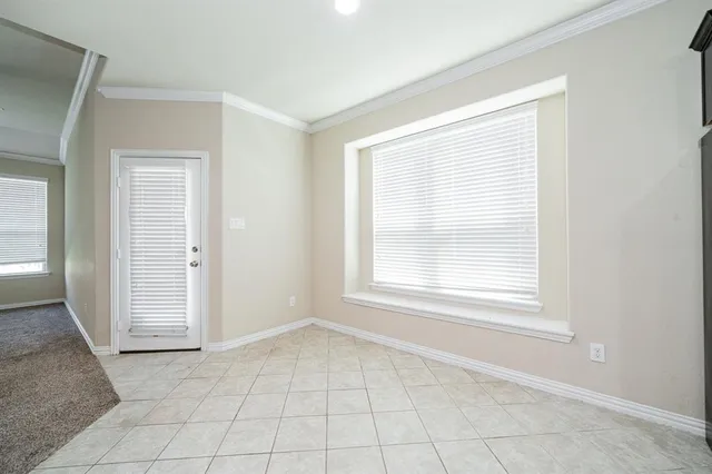 an empty room with chandelier fan and windows