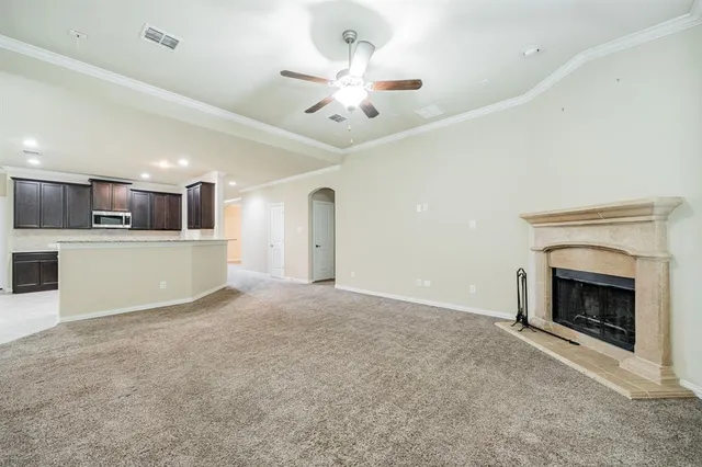 an empty room with chandelier fan and windows